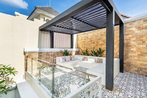 Un espace extérieur moderne, aménagé avec une balustrade en verre, des carreaux de sol à motifs et un mur en pierre en arrière-plan.