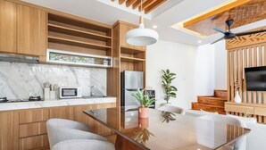 Eine moderne Küche mit Holzausbau, einem Glastisch und einer eingebauten Mikrowelle.