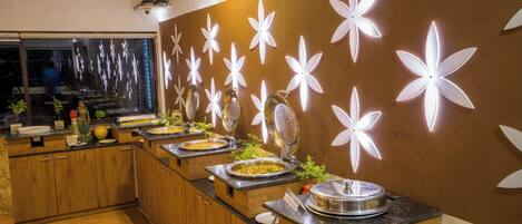 A buffet setup with multiple food stations and a decorative wall with illuminated floral patterns.