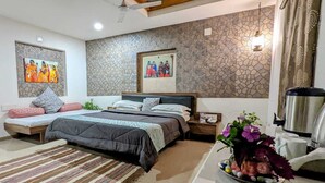 A bedroom with a large bed, two nightstands, a coffee maker, and artwork on the walls.