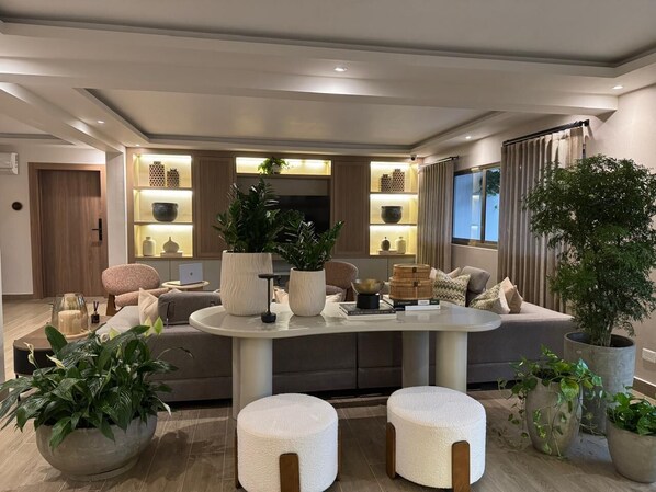A modern living room with a central island, seating area, and a dining space.