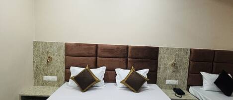 A hotel room with a large bed, two bedside tables, a headboard, and a ceiling light fixture.
