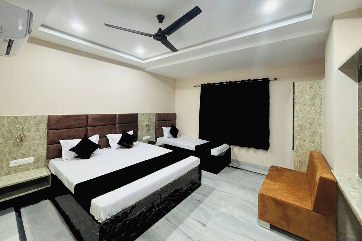 A hotel room with two beds, a ceiling fan, a marble floor, and a small seating area.