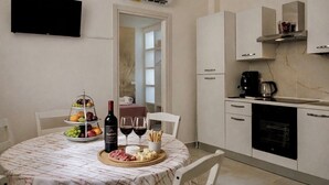 Een compacte, moderne keuken met een eettafel gedekt voor twee personen, met een fruitschaal, kaas en wijn.
