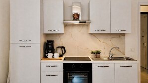 Een moderne keuken met witte kastjes, een ingebouwde oven, een koffiezetapparaat en een spoelbak.