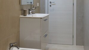 Een badkamer met een witte wastafel, spiegel en deur.