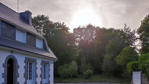 A two-story house with a gravel driveway and a stone wall. - The little house in the forest (Clohars-Fouesnant)