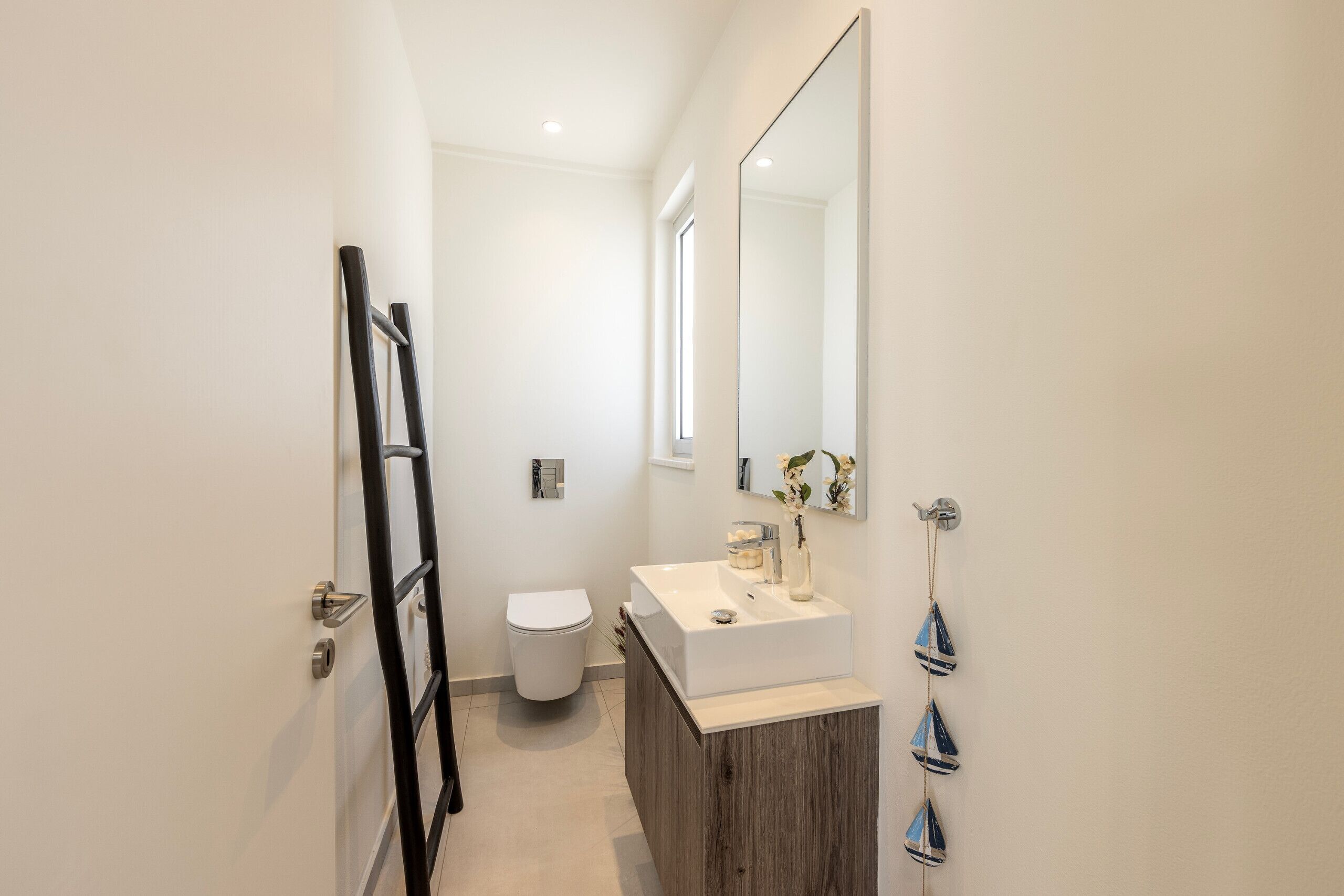 Une salle de bain moderne avec un lavabo blanc, un miroir et des toilettes.