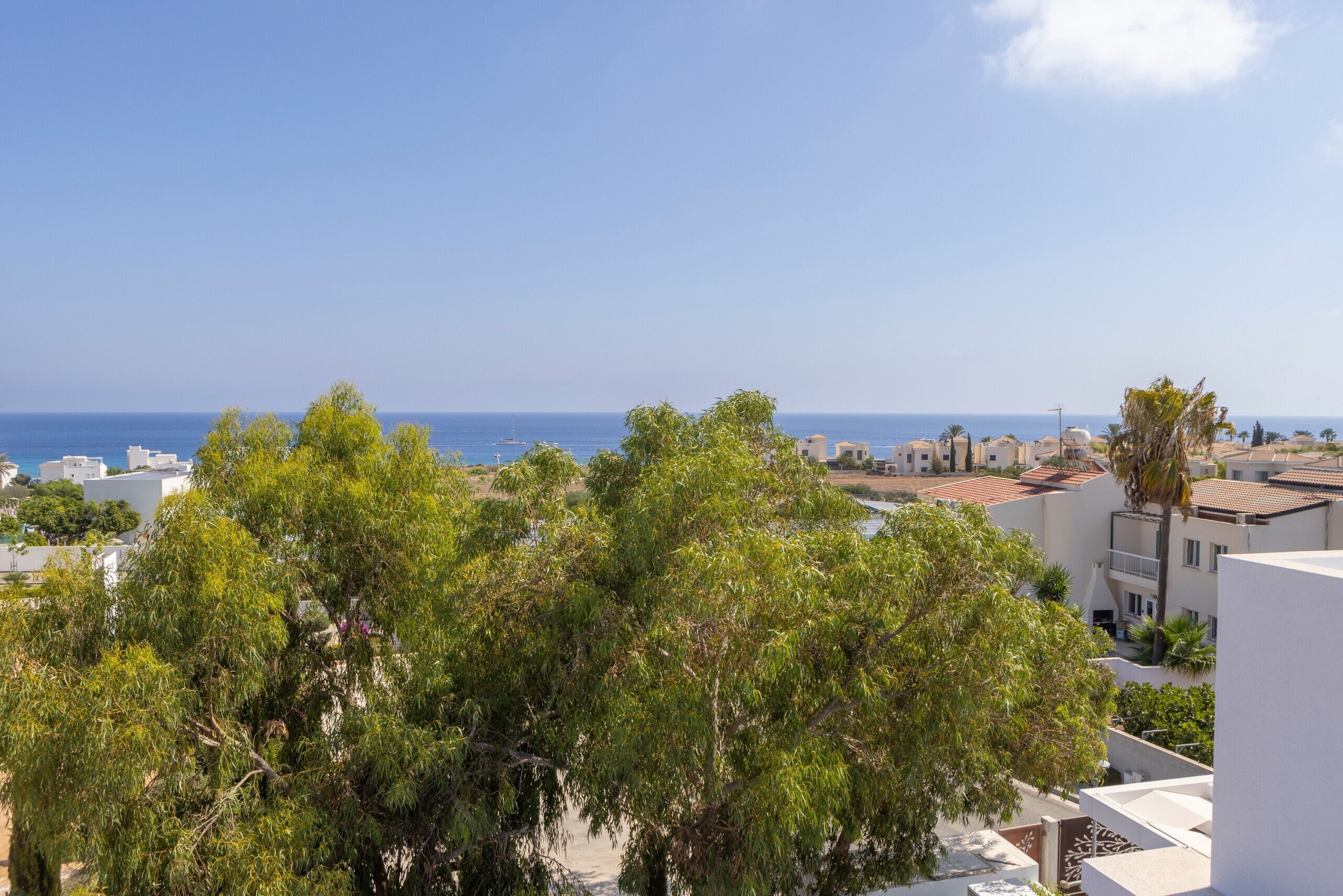 A coastal view with buildings, trees, and the sea.