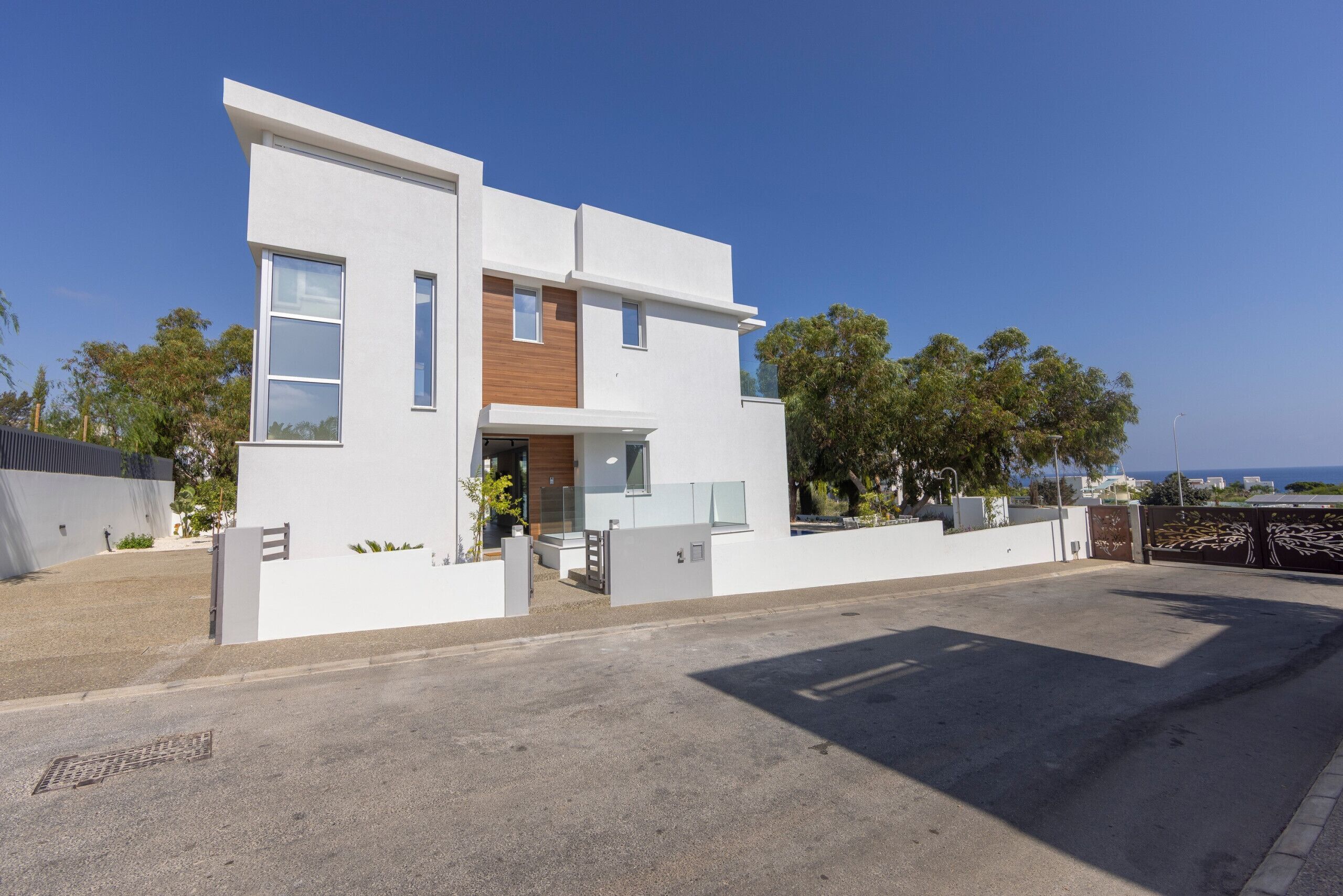 Una casa moderna de dos plantas con techo plano, ventanas grandes y un pequeño porche delantero.