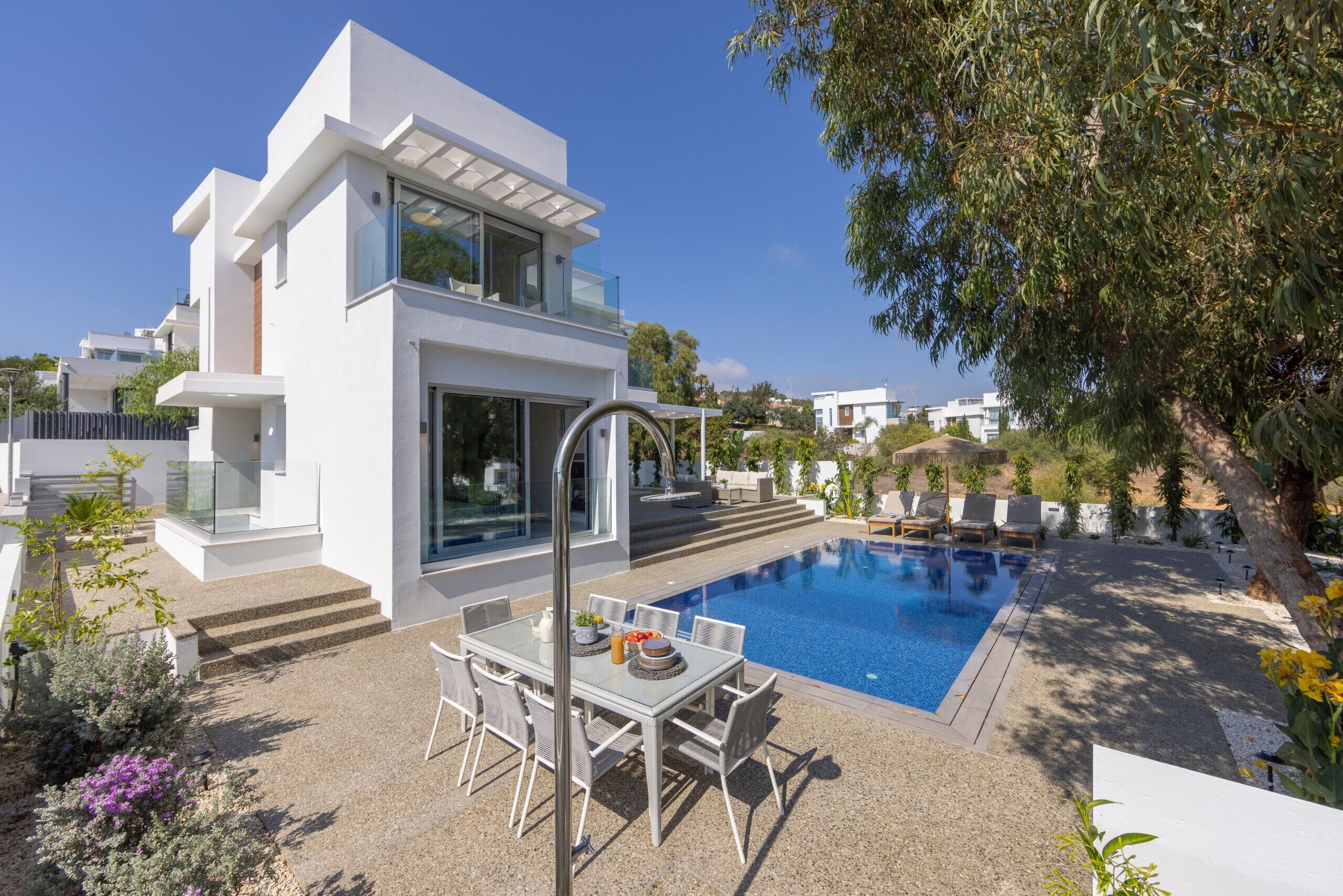 A modern two-story house with a swimming pool, outdoor seating, and a well-maintained garden.