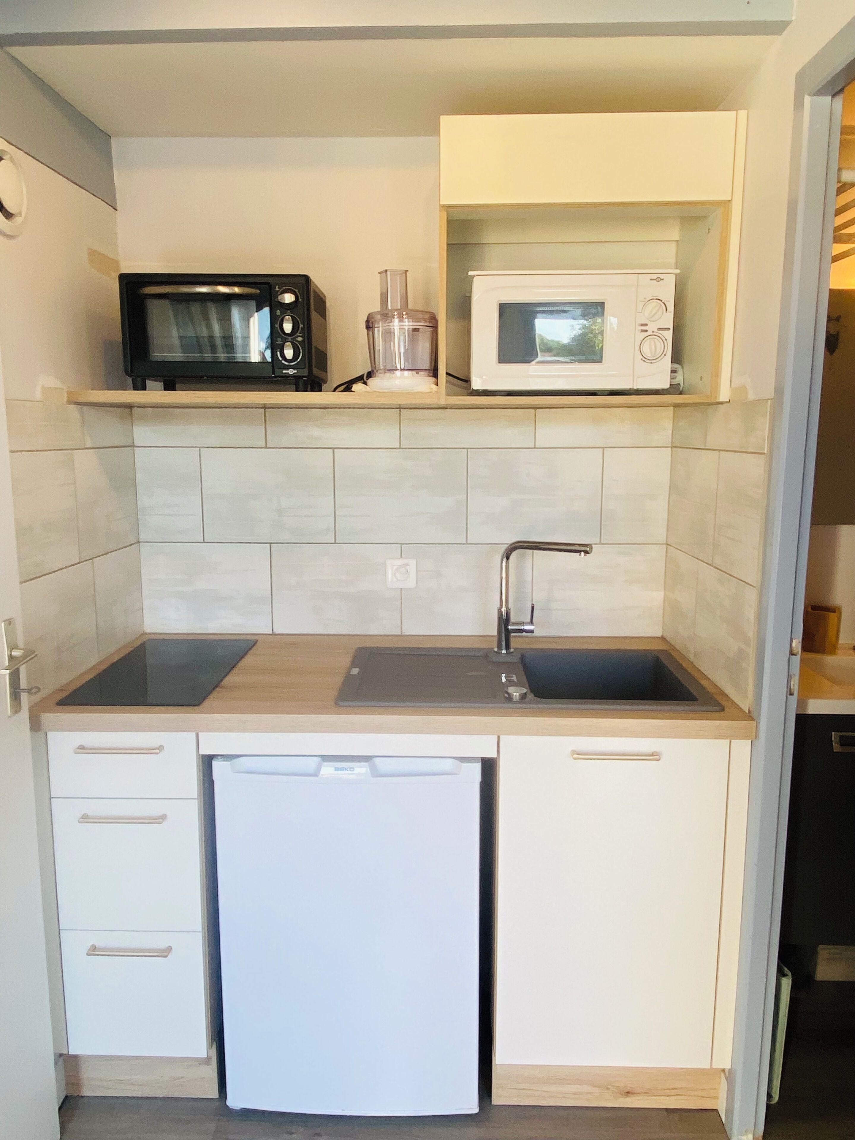 A compact kitchen with a microwave, a blender, and a dishwasher.
