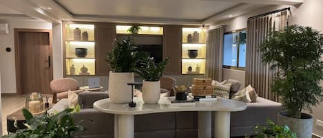 A modern living room with a central island, seating area, and a dining space.