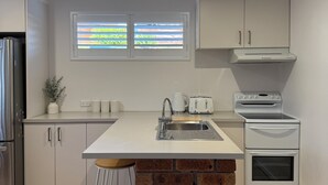 Een moderne keuken met een centraal eiland, roestvrijstalen apparatuur en een accentmuur van baksteen.