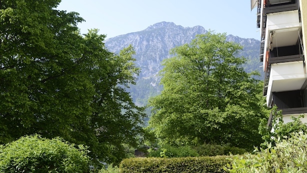 A residential area with a mountain in the background, surrounded by lush greenery and a building with balconies. - Vacation apartment Lona, 1-3 pers., 45 sqm, living/bedroom (Bad Reichenhall)