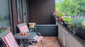 A balcony with a table and chairs, a potted plant, and a view of greenery. - Vacation apartment Lona, 1-3 pers., 45 sqm, living/bedroom (Bad Reichenhall)