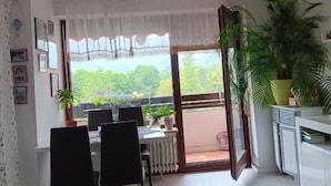 A dining area with a table and chairs, a potted plant, and a view of greenery outside. - Vacation apartment Lona, 1-3 pers., 45 sqm, living/bedroom (Bad Reichenhall)
