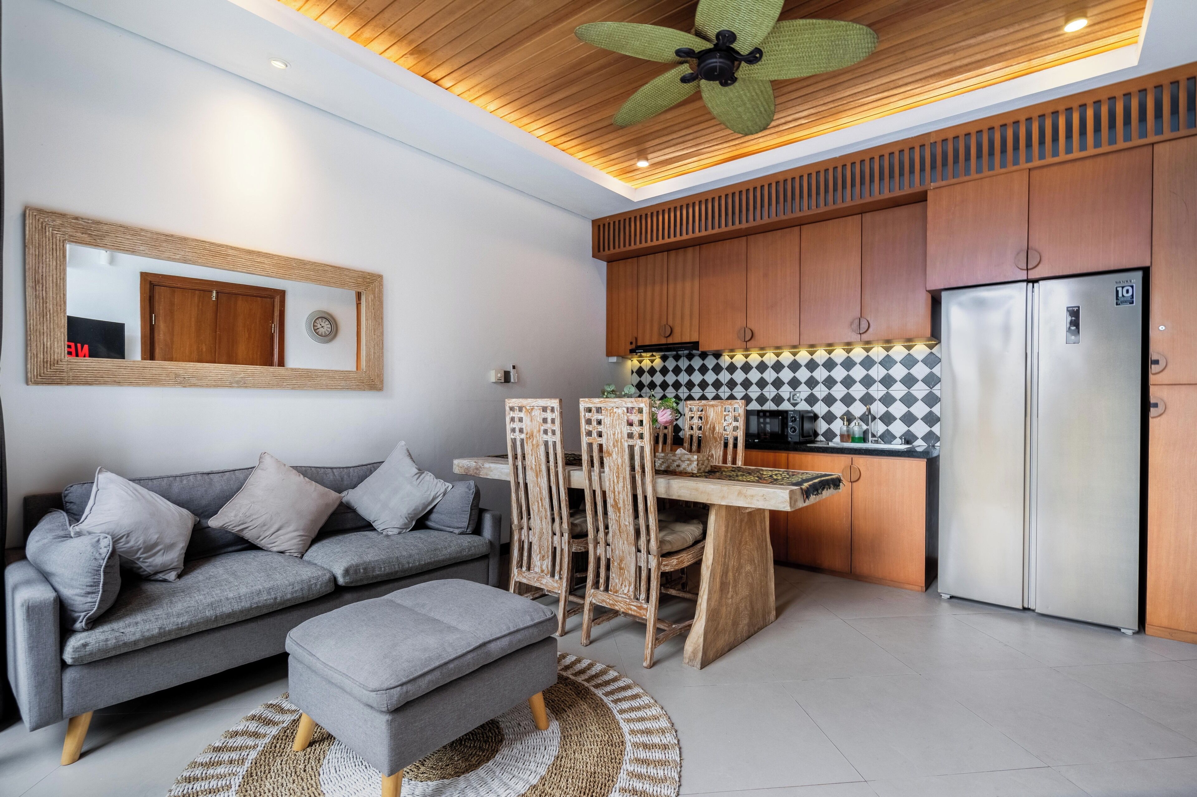 Une cuisine moderne avec des meubles en bois, un réfrigérateur en acier inoxydable et un coin repas comprenant une table et des chaises en bois.