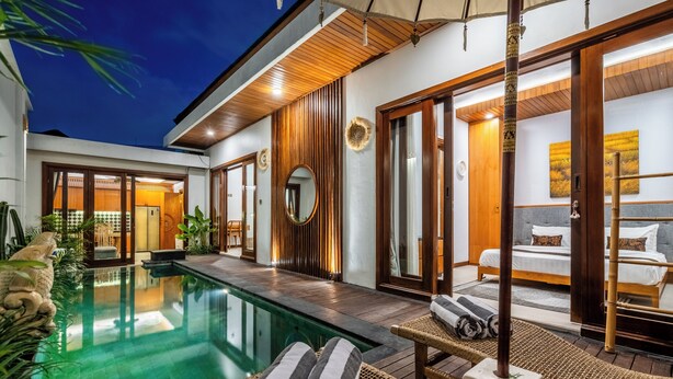 A modern hotel with a swimming pool, wooden accents, and a well-lit interior. - Private Pool Villa Dacira by Orivista (Canggu)