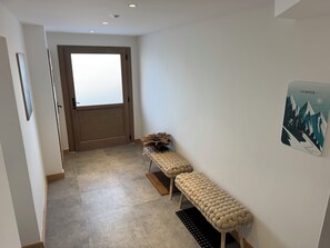 Un pasillo con un banco, una puerta y un cartel en la pared.
