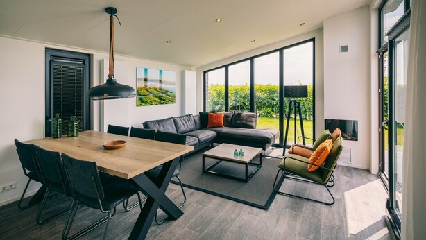A modern living room with a dining area, large windows, and a view of greenery. - Bungalow in Herkingen between nature reserve (Herkingen)