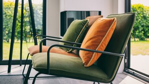 A modern chair with a metal frame and cushioned seat, positioned near a window with a view of greenery. - Bungalow in Herkingen between nature reserve (Herkingen)