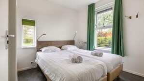 A bedroom with a bed, two windows with curtains, a bedside table, and a wall-mounted light. - Waterfront escape with marina views (Terherne)