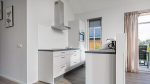 Une cuisine moderne avec des meubles blancs, un four encastré et une grande fenêtre donnant sur l’extérieur.