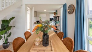 A dining area with a wooden table, brown chairs, a vase with flowers, and a potted plant. - Tranquil villa for 6 guests with patio (Tynaarlo)