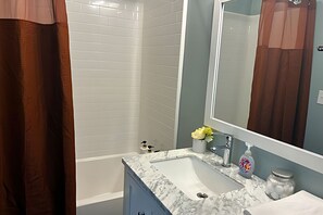 A bathroom with a white sink, a mirror, and a shower area.