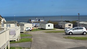 Ein Küsten-Campingpark mit mehreren Mobilheimen, einem Parkplatz und Blick auf das Meer.