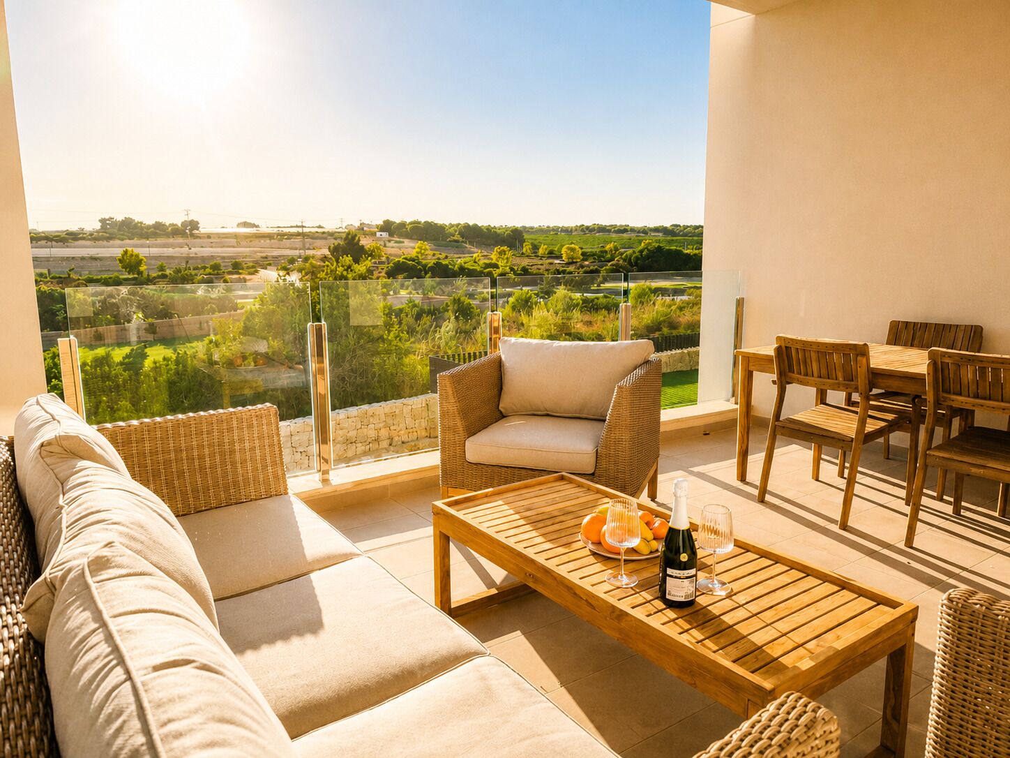 Un balcon avec un canapé en osier, une table en bois avec une bouteille et des verres, et un ensemble de mobilier de salle à manger.