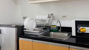 Una cucina con mobili bianchi, lavastoviglie, forno a microonde e lavello.