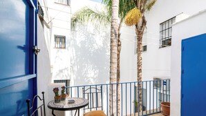 A courtyard with a blue door, a round table with chairs, and a potted plant. - Virgen de la Luz. 2-bedrooms, 2-bathrooms (Sevilla)
