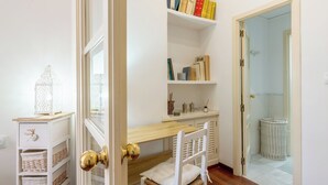 A room with a wooden desk, a white chair, a bookshelf with books, and a white door with a brass doorknob. - Virgen de la Luz. 2-bedrooms, 2-bathrooms (Sevilla)