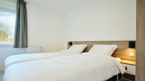 A double bed with white bedding, a wooden headboard, bedside tables, and a window with curtains. - Stylish Comfort by the Opal Coast (Berck-Sur-Mer)