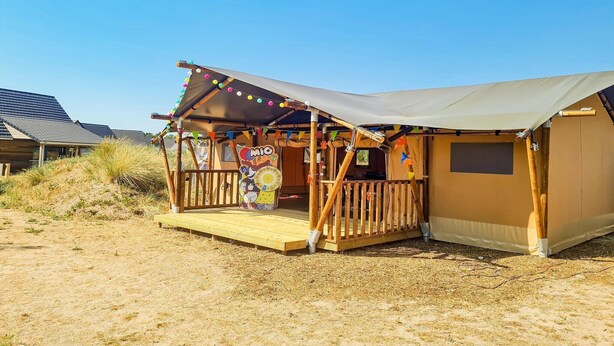 A beachside wooden structure with a deck, a covered seating area, and a tent-like room. - Stylish Comfort by the Opal Coast (Berck-Sur-Mer)