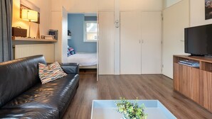 A modern living room with a leather sofa, a coffee table, a TV, and a wardrobe. - Water villa with outdoor spa, jetty (Eernewoud)