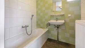 A bathroom with a white bathtub, a sink, and a mirror. - Water villa with outdoor spa, jetty (Eernewoud)