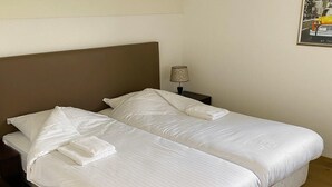 A double bed with white bedding and a brown headboard in a hotel room.