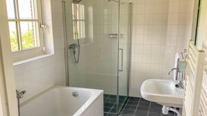 A bathroom with a bathtub, a glass-enclosed shower, and a sink.