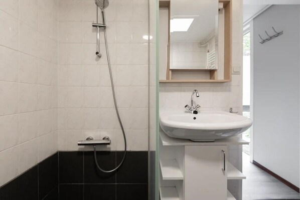 Un baño moderno con ducha, lavamanos y espejo.