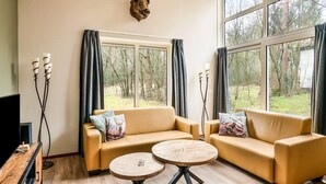 A living room with two sofas, a coffee table, and a mounted animal head on the wall. - Cosy forest bungalow with sauna (Kootwijk)
