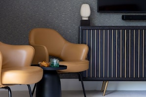 A modern living room with two leather armchairs, a small table with a glass, and a dark wood paneling cabinet. - Gable View (Combeinteignhead)