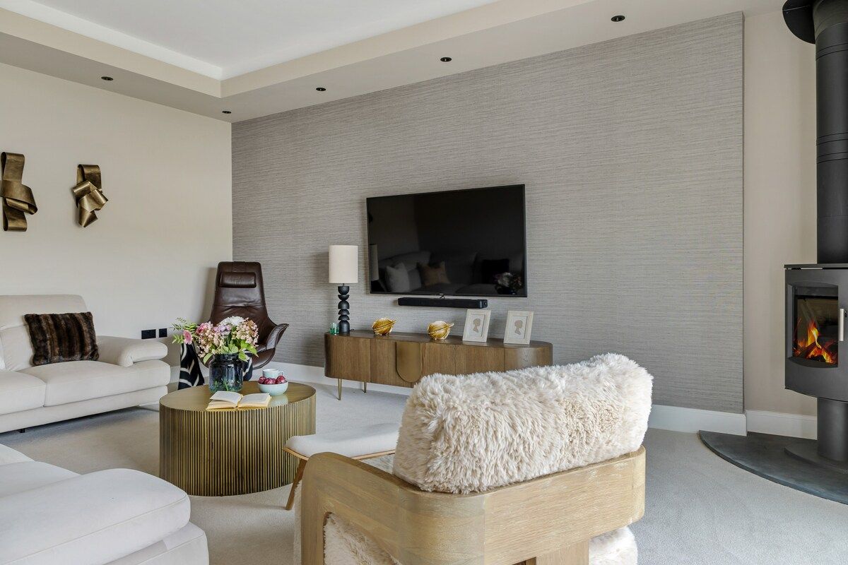 A modern living room with a sofa, armchair, and a fireplace.