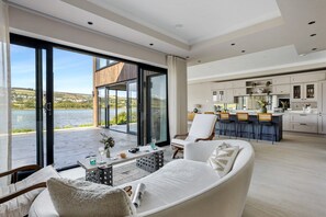 A modern living room with a large sliding glass door leading to a balcony with a view of a lake. - Gable View (Combeinteignhead)