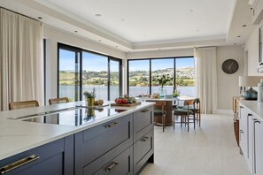 A modern kitchen with a large island, dining area, and a view of the outdoors. - Gable View (Combeinteignhead)