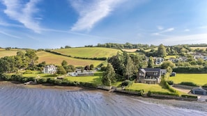 A coastal property with multiple houses, a beach, and rolling hills in the background.