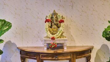 A wooden table with a statue on top, surrounded by green leaves.