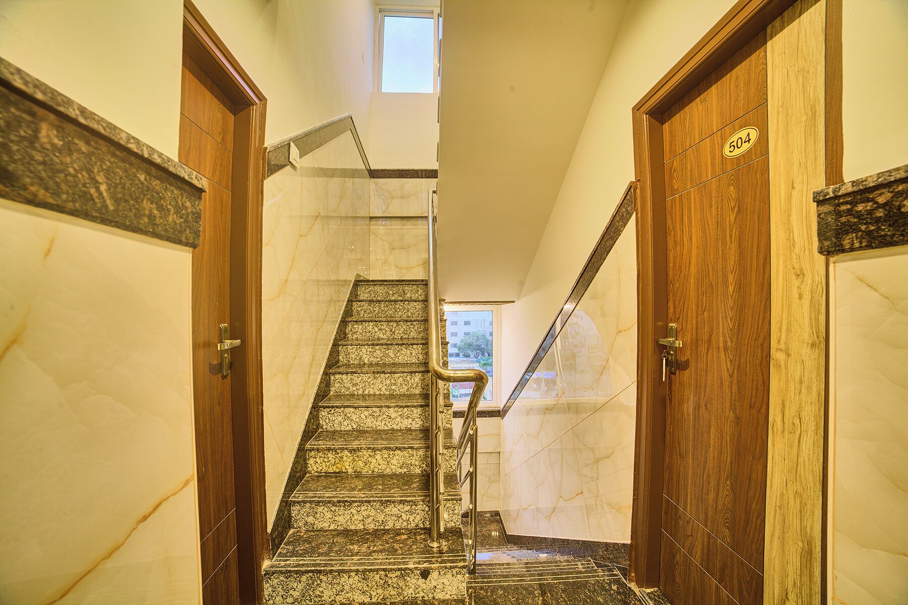 A marble staircase with a handrail, leading to a door marked with the number 504.